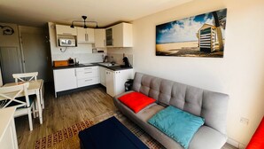 A compact living space with a kitchenette, a sofa with cushions, a dining table, and a patterned rug. - Apartment near the beach - 4 guests (Argelès-sur-Mer)