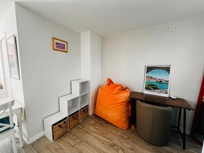 Ein Zimmer mit weißer Wand, Holzboden, weißem Stuhl, einem kleinen Tisch mit einem Bild und einem Sitzsack.