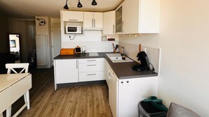 A compact kitchen with white cabinets, a microwave, a sink, and a small countertop area. - Apartment near the beach - 4 guests (Argelès-sur-Mer)