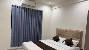 Una habitación de hotel con una cama, un ventilador de techo y un equipo de aire acondicionado.