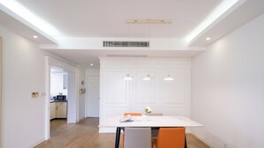 Et moderne spiseområde med et hvidt bord, to orange stole og hængende lys.