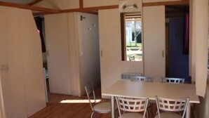 Une pièce avec un plancher en bois, une table entourée de chaises, une porte et une fenêtre.