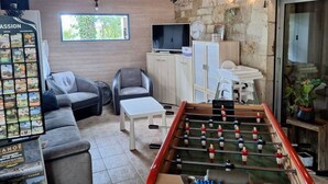 Une pièce confortable avec un baby-foot, une télévision, un canapé et une petite table.