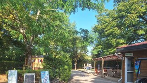 A pathway leading to a snack bar with a covered seating area, surrounded by trees. - Family mobile home - 6 guests (Rocamadour)
