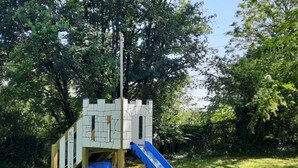 Estrutura de recreação com tema de castelo, incluindo escorregador e parede de escalada, em um parque.