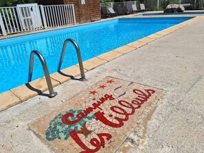 Ein Schwimmbecken mit einer gefliesten Liegefläche, auf der eine französische Schrift steht.