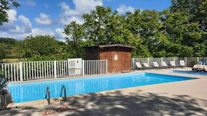 Una piscina con estructura de madera, vallas blancas y sillas de descanso.