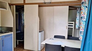 Una cocina compacta con estufa, un refrigerador pequeño y una zona de comedor con mesa y sillas.