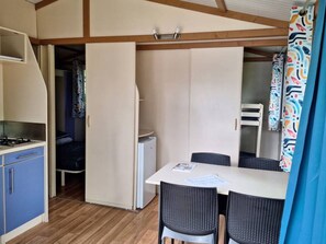 Eine kompakte Küche mit Herd, einem kleinen Kühlschrank und einem Essbereich mit Tisch und Stühlen.