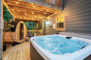 Eine Holzterrasse mit Whirlpool, einer Holzsauna und Lichterketten.