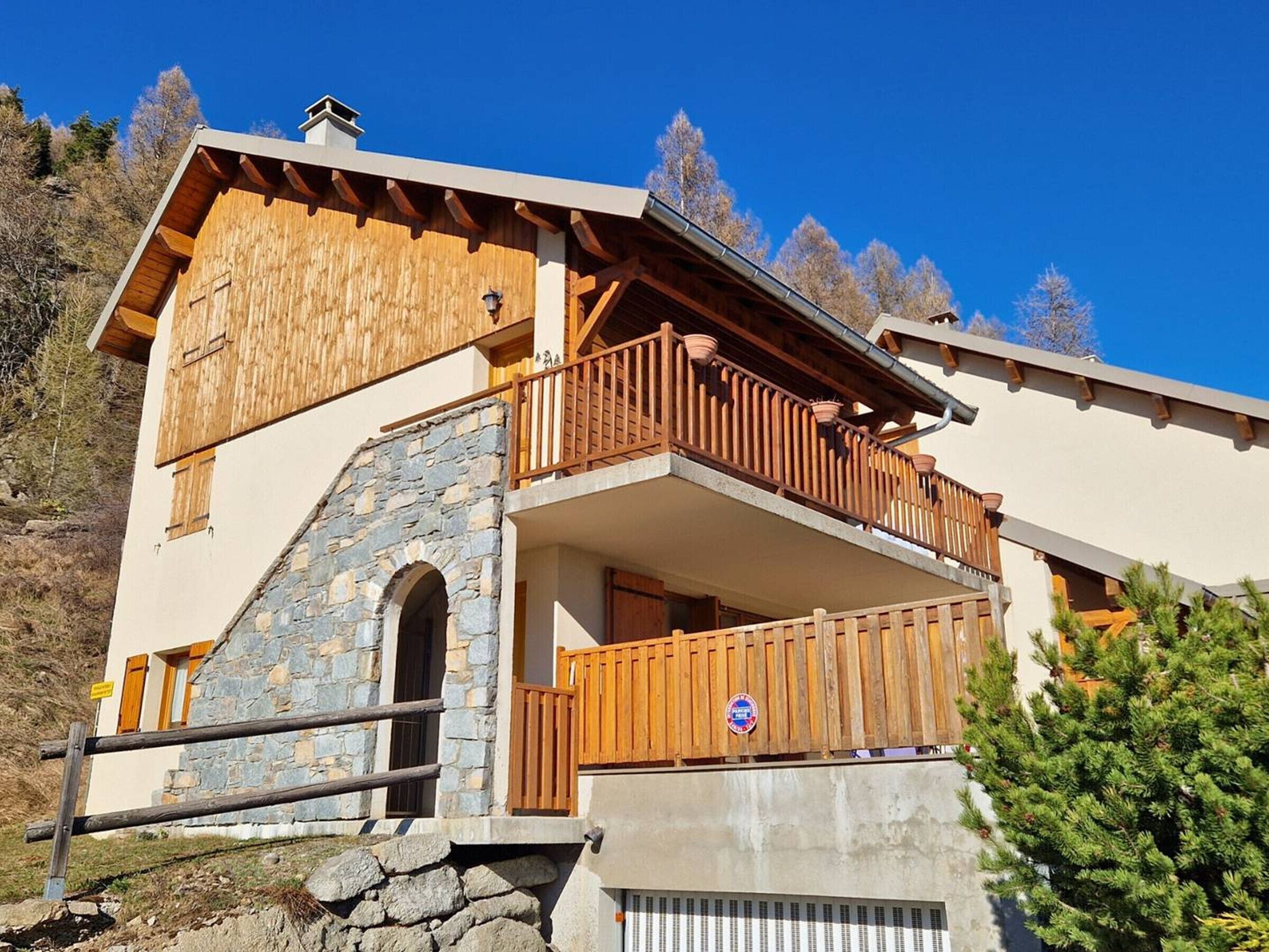 Un edificio de dos pisos con fachada de piedra, barandas de balcón de madera y cielo despejado.