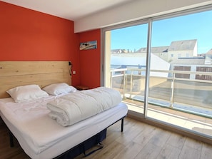 Ein Schlafzimmer mit großem Fenster, Holz-Kopfteil und Blick auf Gebäude.