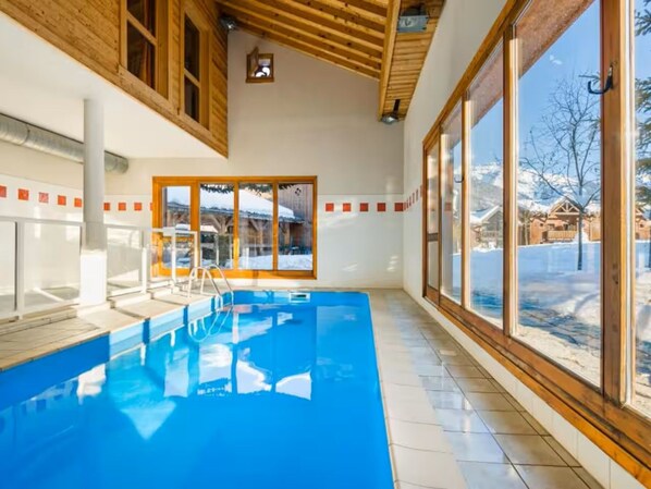 An indoor swimming pool with wooden beams, large windows, and a view of a snowy landscape. - Quiet apartment, pets allowed - 4 guests (Samoëns)
