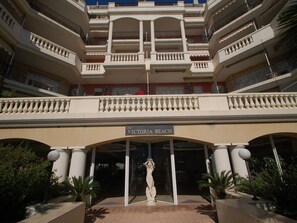 Ein mehrstöckiges Hotel mit zentralem Eingang, Säulen und einer Statue.