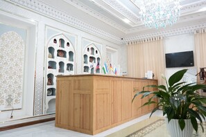 Una zona de recepción con mostrador de madera, paneles decorativos en la pared y un candelabro.