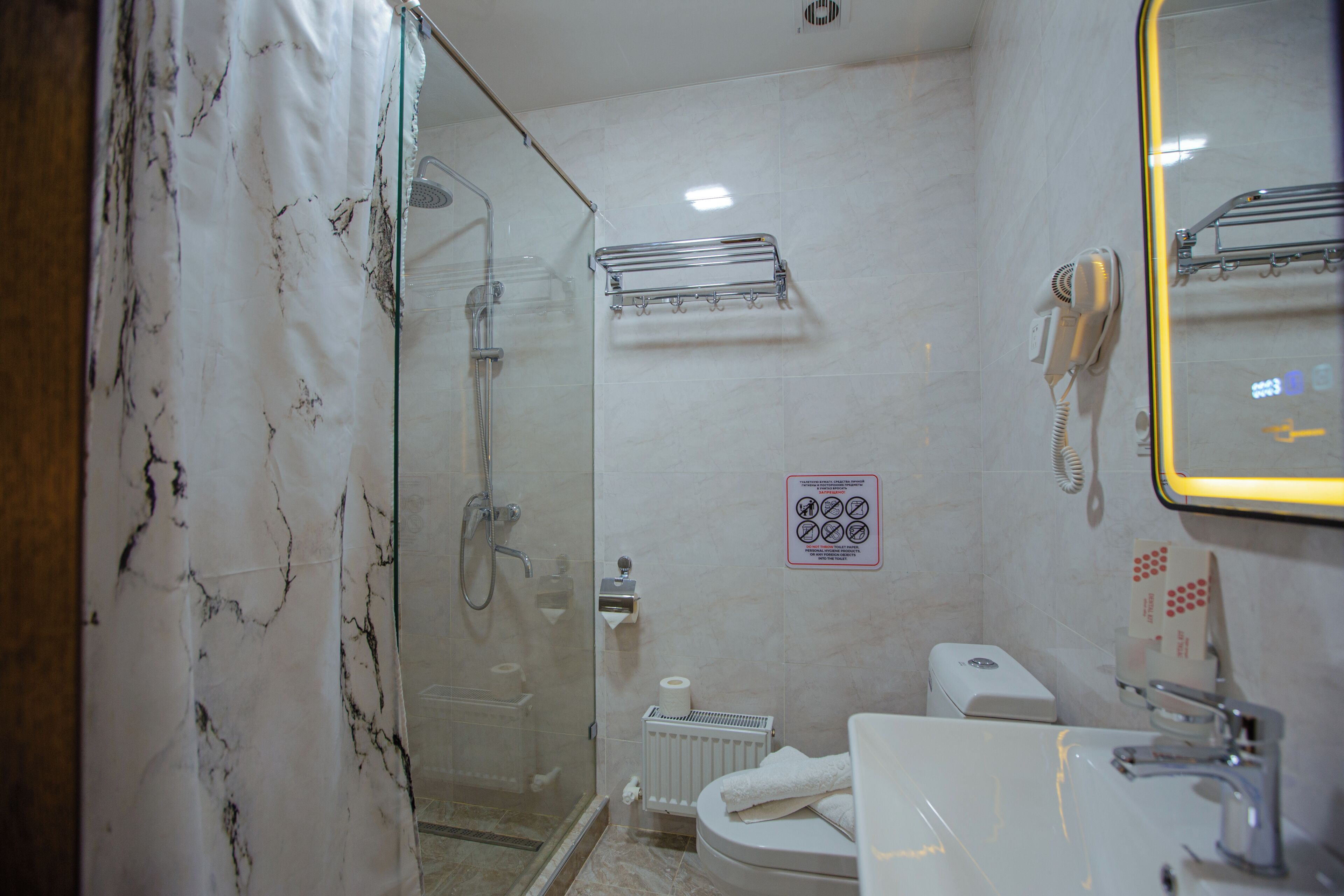 Un baño con ducha de mampara de vidrio, inodoro, lavamanos y espejo.