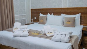 A neatly made hotel bed with towels and a blanket, a wooden headboard, and a nightstand with a lamp. - Shergiron Plaza (Bukhara)