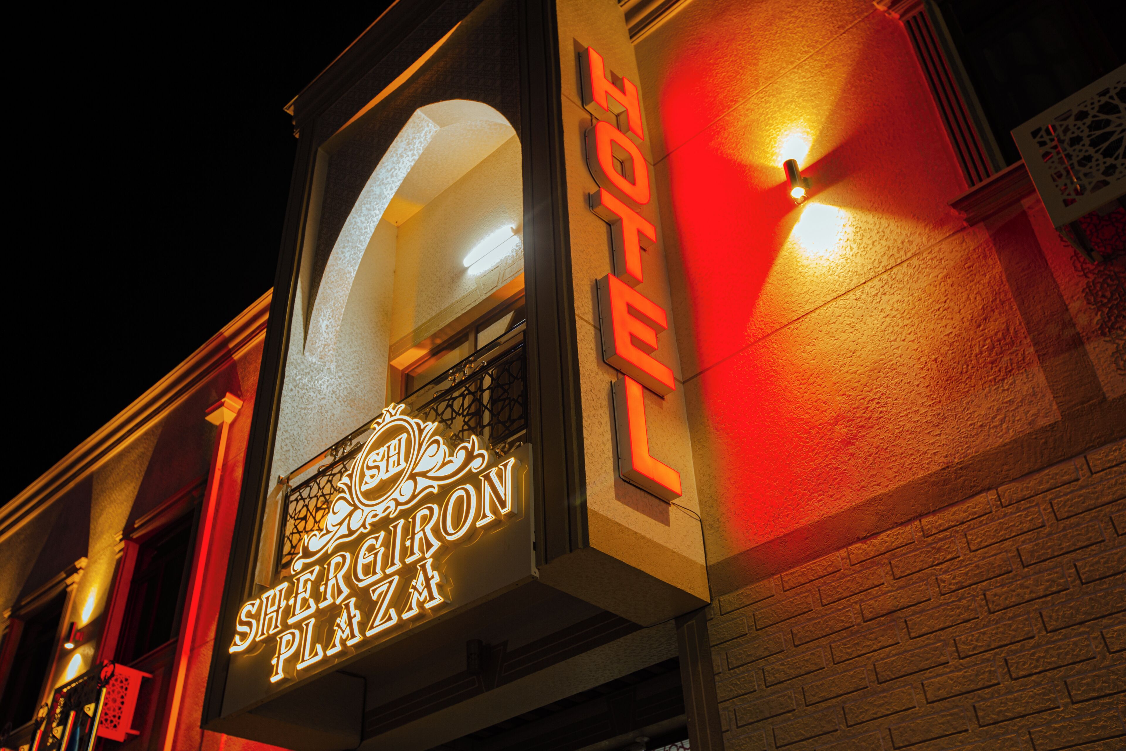 A building with a neon sign that reads 'Sheraton Plaza' and a red light on the wall.