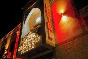A building with a neon sign that reads 'Sheraton Plaza' and a red light on the wall.