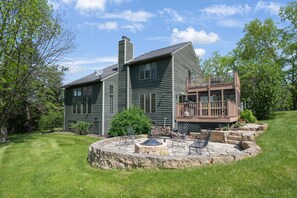 A two-story house with a stone fire pit and outdoor seating, surrounded by a well-maintained lawn and trees. - WV11 - An Eagle Ridge Resort & Spa Rental with Full Resort Amenities and Owners Club Access! (Galena)