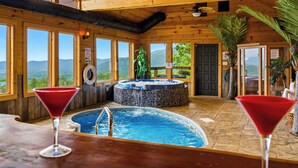 Ein Holzinnenraum mit Whirlpool, Schwimmbad und zwei Martini-Gläsern.