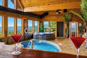 A wooden interior with a hot tub, a pool, and two martini glasses. - Private Mountain Resort | Indoor Pool, Theater & Sleeps 30 (Sevierville)