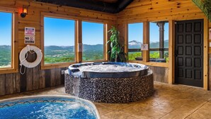 Eine Holzhütte mit Whirlpool, Pool und großen Fenstern mit Bergblick.