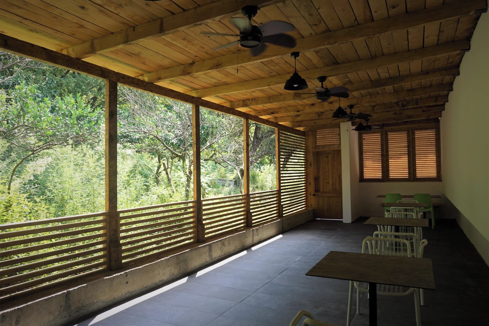 A room with large windows, ceiling fans, and a view of greenery.