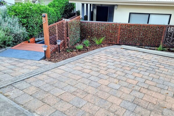 A paved driveway leading to a house with a wooden fence and a mailbox.