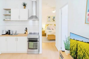 A modern kitchen with white cabinets, a stainless steel range, and a built-in oven.