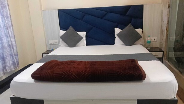 Una cama con cabecera oscura, ropa de cama blanca y dos almohadas.