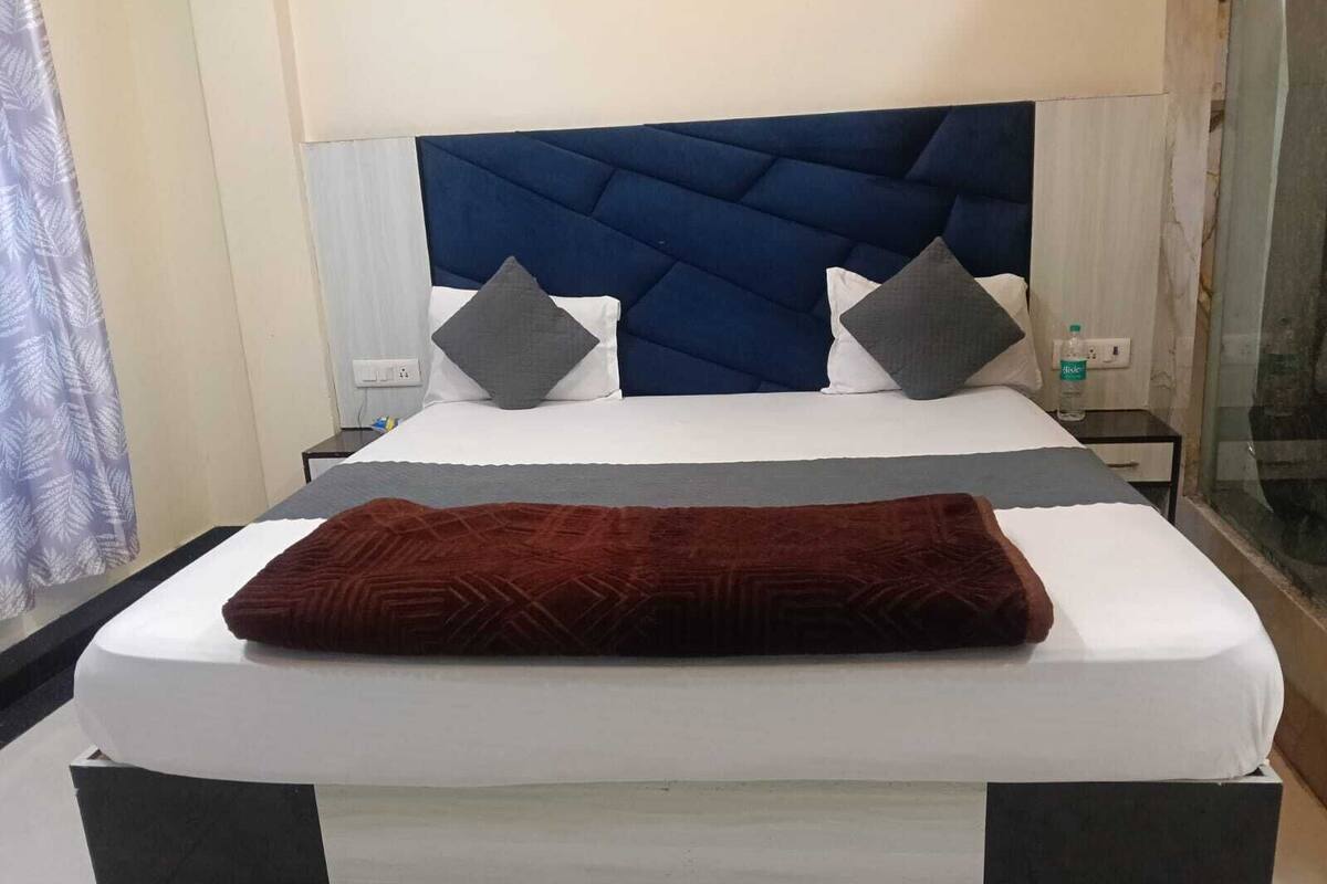 Una cama con cabecera oscura, ropa de cama blanca y dos almohadas.