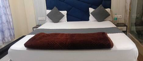 A bed with a dark headboard, white bedding, and two pillows.