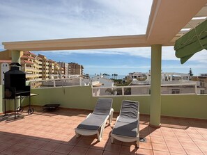 A rooftop terrace with two sun loungers, a grill, and a view of buildings and the sea. - Delfines III bl.IV esc.3 2º Solo Familias! (Playa Xeraco)