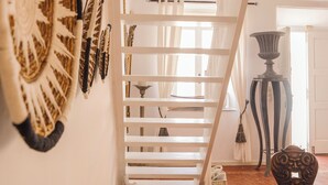 Een trap met witte leuningen, een klein tafeltje met een wit object, en een decoratieve wandversiering.