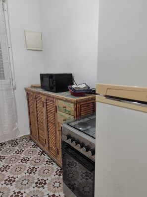 A kitchen with a stove, microwave, and wooden cabinet. - Dar Christelle villa 4 persons In the countryside (Ounagha)