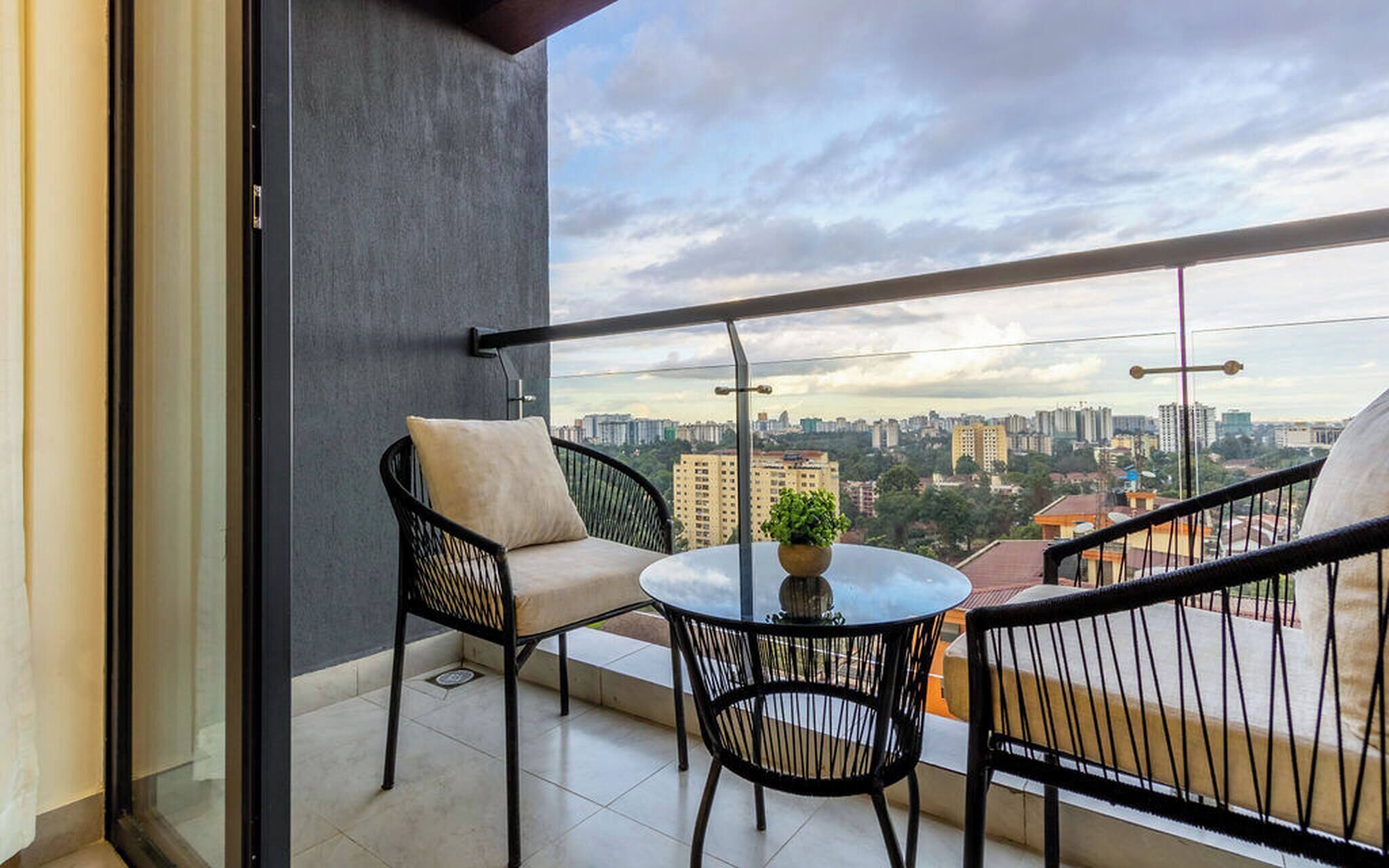 Un balcon avec deux chaises, une petite table et un pot de fleurs.