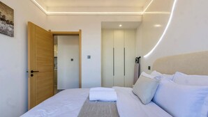 Een slaapkamer met een bed, een houten deur, een kledingkast en een schilderij aan de muur.