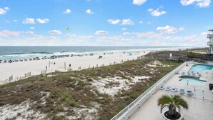 Une vue sur la plage avec une piscine, des parasols et un poste de surveillance pour les sauveteurs.