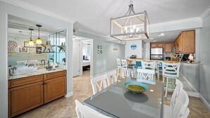 Une cuisine moderne avec des meubles en bois, un plan de travail en marbre et un coin repas avec des chaises blanches.
