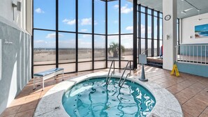 Un espace piscine avec vue sur la plage, un banc et un panneau de sécurité.