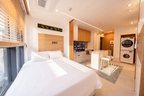 Ein modernes Hotelzimmer mit Bett, Schreibtisch, Fernseher und Waschmaschine.