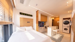 Ein modernes Hotelzimmer mit Bett, Schreibtisch, Fernseher und Waschmaschine.