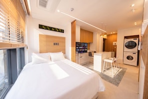Une chambre d’hôtel moderne équipée d’un lit, d’un bureau, d’une télévision et d’un lave-linge.