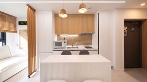 Eine moderne Küche mit Holzschränken, einer weißen Arbeitsplatte und Pendelleuchten.