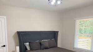 A bedroom with a bed, bedside table, lamp, and a window with blinds. - Welcome to Sandtown Villa—your home away from home. (Atlanta)