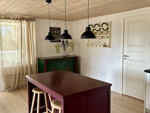 Una cocina con una isla de madera, luces colgantes, un armario verde y una puerta blanca.