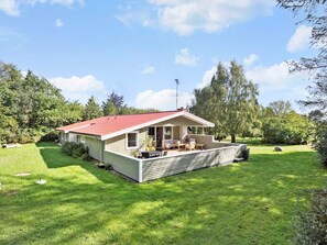 A single-story house with a red roof, a covered patio with furniture, and a well-maintained lawn. - 4 Star Holiday Home in Oro (Orø)
