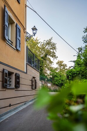 Una calle estrecha con un edificio que tiene un balcón, un farol y una valla.