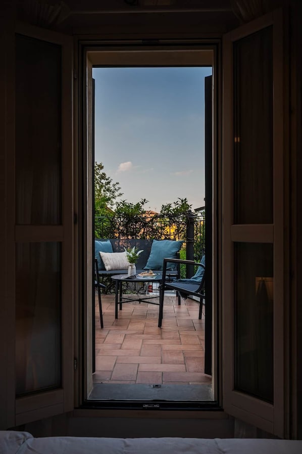 Puerta abierta que da a un patio con zona de estar y vistas a follaje.